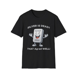 Puede incluir: Camiseta negra con un gráfico de un personaje de barra de plata sonriente. El texto de arriba dice "SILVER IS DEAD?" y debajo "THAT Ag-ed WELL!". La barra de plata tiene la palabra "SILVER" y "999.9" impresas.