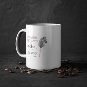 May include: White ceramic mug with a black and gray hobby horse illustration and the text "Just a girl who loves Hobby Horsing".