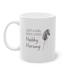 May include: White ceramic mug with a gray stick horse illustration and the text "Just a girl who loves Hobby Horsing".