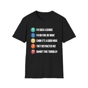 May include: Black t-shirt with white text and colorful exclamation point graphics. The text includes phrases like "I'm such a genius" and "Damnit time trouble!!" A casual, graphic tee.