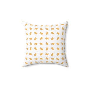 May include: Square throw pillow with a white background and a repeating pattern of small, orange fish-shaped crackers. The pillow is a square shape, perfect for a couch or bed.