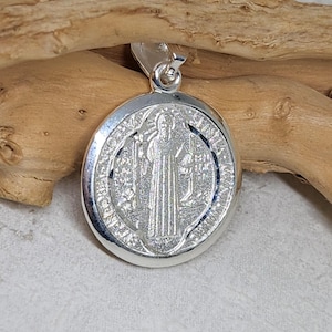 May include: Silver Saint Christopher medal pendant featuring a detailed image of Saint Christopher carrying a child. The medal is oval shaped and has a raised rim.