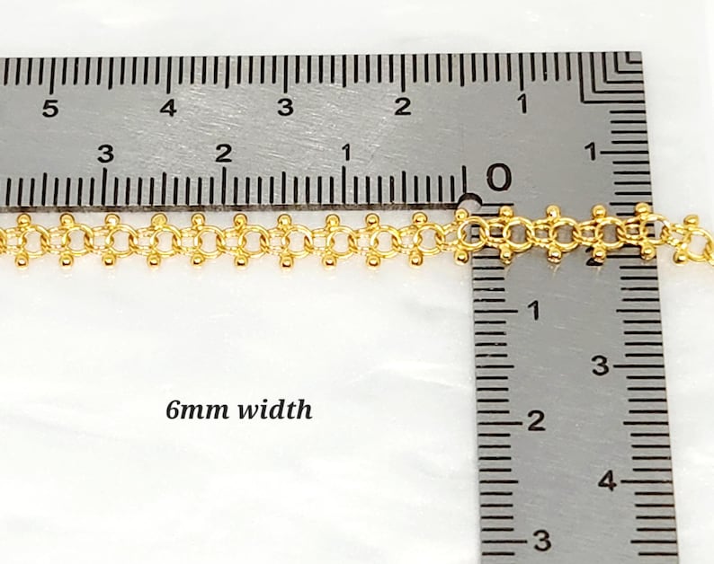 Pu&ograve; includere: Primo piano di una catena d'oro di 6 mm di larghezza, misurata con un righello. La catena &egrave; composta da piccoli anelli rotondi.