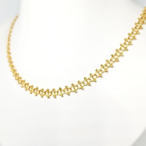 Pu&ograve; includere: Una collana a catena d'oro con un design delicato e intricato. La catena &egrave; composta da piccoli anelli rotondi che sono collegati in un motivo ripetitivo.