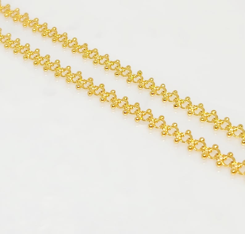 Pu&ograve; includere: Una collana a catena d'oro con un design delicato e intricato. La catena &egrave; composta da piccole perle rotonde che sono collegate tra loro in un motivo ripetitivo.