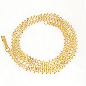 Pu&ograve; includere: Una collana a catena d'oro con un design delicato e intricato. La catena &egrave; composta da piccole perle rotonde che sono collegate in un motivo di cerchi intrecciati. La collana ha una chiusura a moschettone.