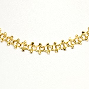 Pu&ograve; includere: Una collana a catena dorata con un design delicato che presenta piccole perle rotonde. La catena &egrave; composta da cerchi interconnessi con una perla in ogni punto in cui i cerchi si incontrano.