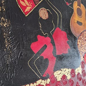 May include: A black canvas painting featuring a red and gold silhouette of a flamenco dancer. The dancer is holding a red fan and is wearing a red dress with gold accents. The background is black with gold musical notes.