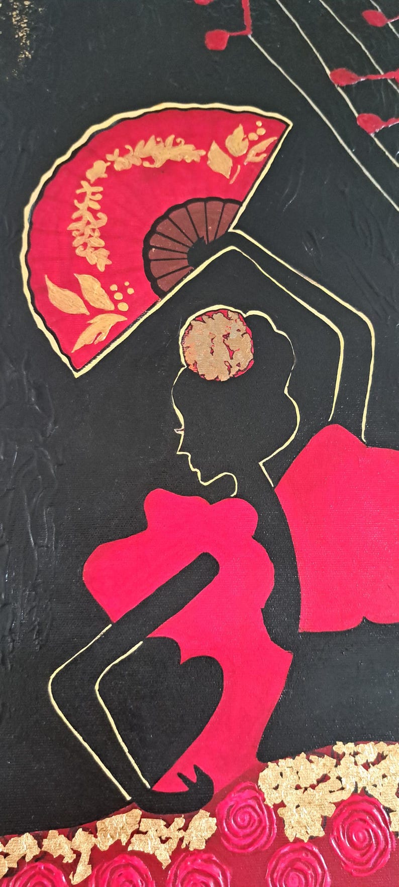 May include: A black and red silhouette of a flamenco dancer with a red fan and gold accents. The dancer is wearing a red dress and has a gold flower in her hair. The background is black with gold accents.