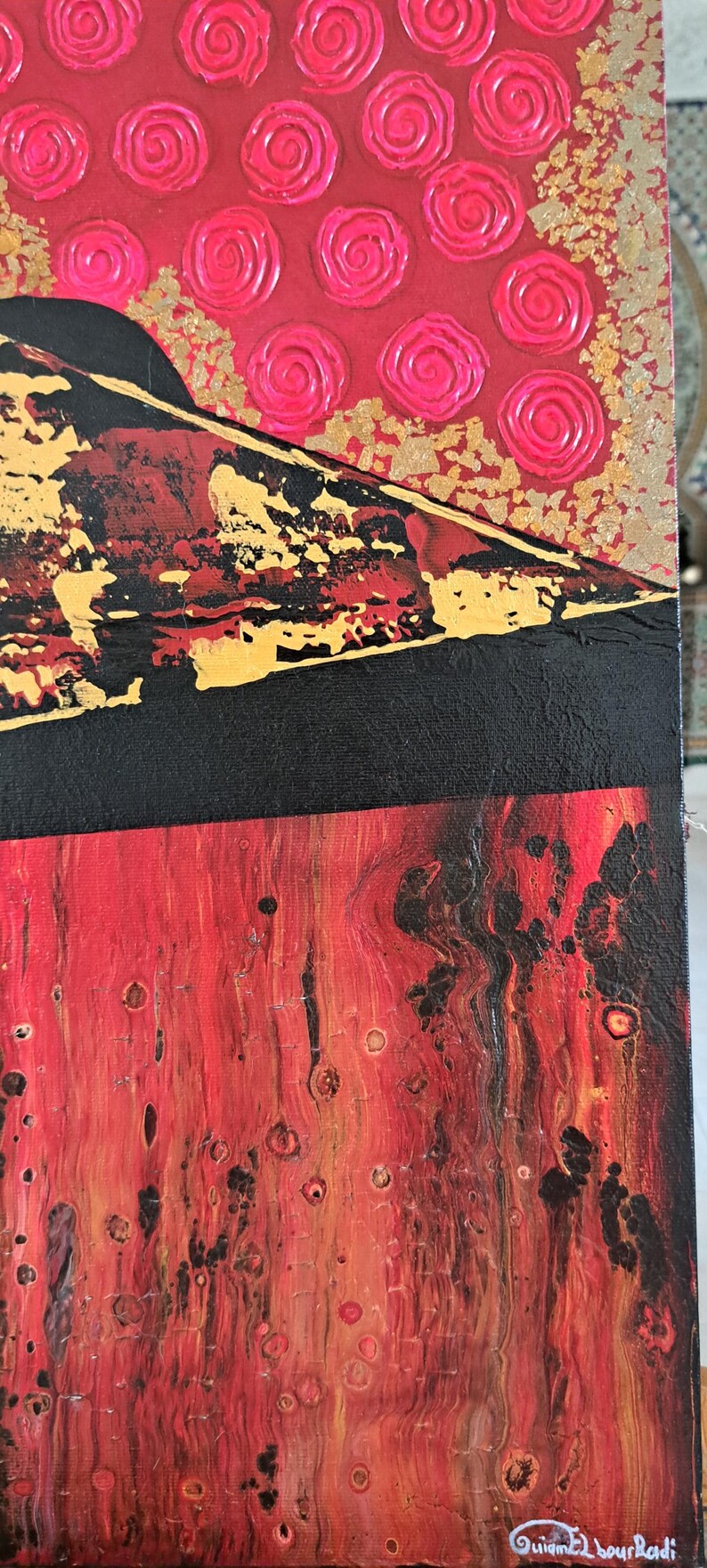 May include: Abstract painting on canvas with a red, black and gold colour scheme. The top portion of the painting features a pattern of pink swirls on a red background. The bottom portion of the painting features a red and black abstract design with gold accents. The painting is signed "Guimel Bourkadi" in the lower right corner.