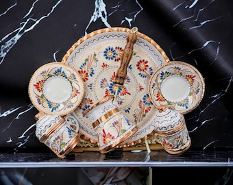 May include: A set of Turkish coffee cups and saucers with intricate floral designs in shades of blue, red, and gold. The set includes a traditional coffee pot and a sugar bowl, all with matching designs.