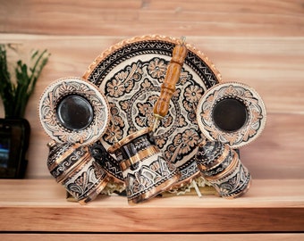 May include: A traditional Turkish coffee set with intricate floral designs. The set includes a copper coffee pot, four cups, and a serving tray. The cups and tray are decorated with black and white floral patterns.