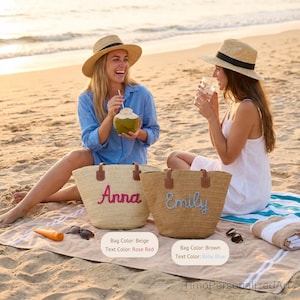 May include: Two woven straw tote bags with brown leather handles. One beige bag features the name Anna in rose red script, and one brown bag features the name Emily in baby blue script. Both bags have open tops and a structured, rounded base.