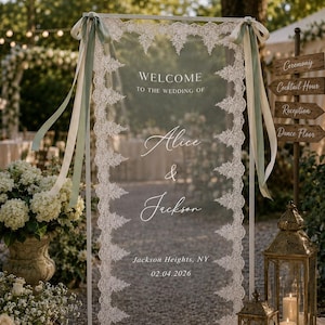 May include: A rectangular clear acrylic wedding welcome sign in a white metal frame, decorated with white lace trim along the vertical edges and sage green ribbons at the top corners. The text reads: WELCOME TO THE WEDDING OF Alice & Jackson, Jackson Heights, NY, 02.04.2026.