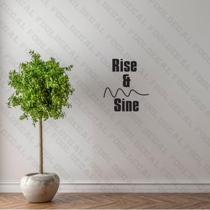Puede incluir: Una calcomanía de pared en blanco y negro con el texto "Rise & Sine" y una línea ondulada debajo. La calcomanía está en una pared blanca con una pequeña planta verde en maceta delante.