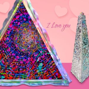 May include: Two iridescent glass pyramids, one with a colorful kaleidoscope design and the other with a textured surface. The text "I Love You" is written in cursive on a pink background.