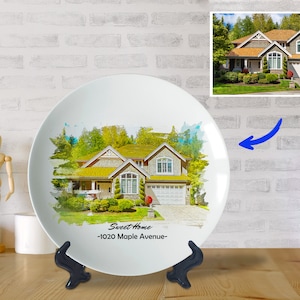 Puede incluir: Plato de cerámica blanco con una pintura de acuarela de una casa con un césped verde y árboles. El texto "Sweet Home - 1020 Maple Avenue -" está impreso en el plato.