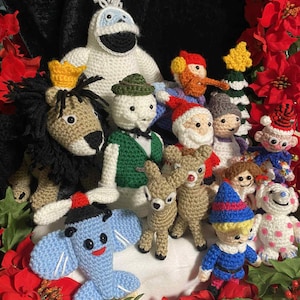 Könnte beinhalten: Eine Sammlung handgefertigter gehäkelter Weihnachtsfiguren, darunter ein Löwe, ein Schneemann, der Weihnachtsmann und Elfen. Die Figuren sind in verschiedenen Farben und Größen gehalten, umgeben von roten Weihnachtssternen und Grün.