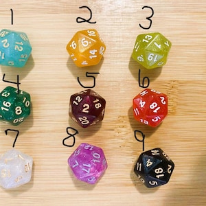 May include: Nine multi-sided dice in various colors, including teal, orange, green, red, purple, and black. Each die has white or gold numbering. The dice are arranged on a light brown wooden surface, perfect for tabletop games.