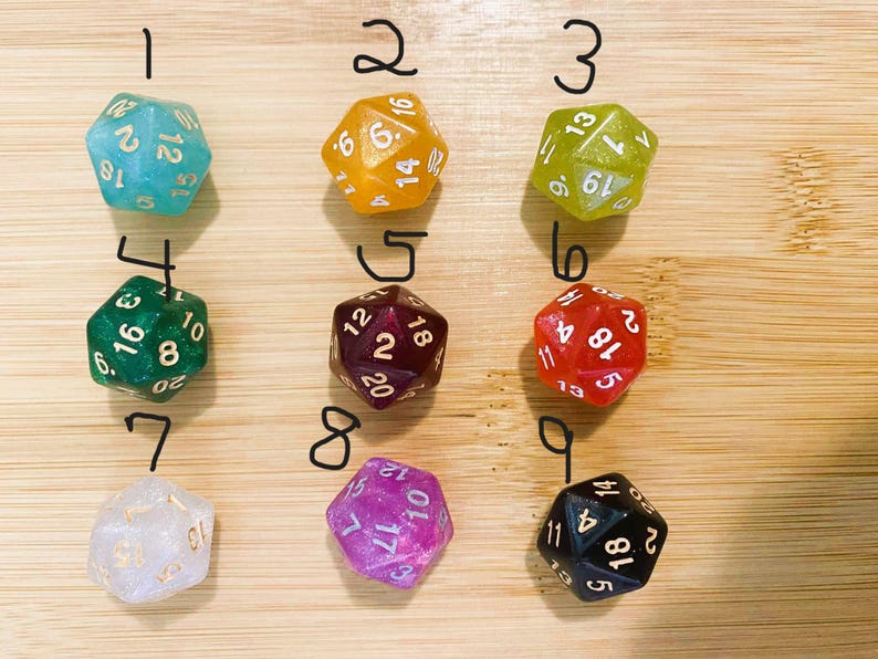 May include: Nine multi-sided dice in various colors, including teal, orange, green, red, purple, and black. Each die has white or gold numbering. The dice are arranged on a light brown wooden surface, perfect for tabletop games.