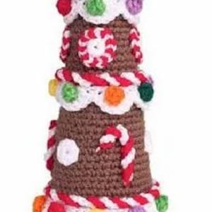 May include: A handcrafted, brown crochet Christmas tree with white, red, and green accents. The tree is decorated with colorful candies, peppermint swirls, and a candy cane. The tree is a festive holiday decoration.