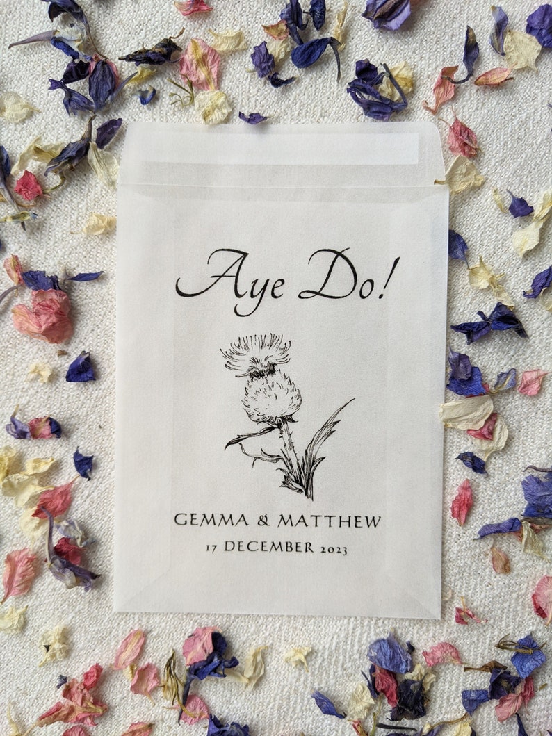 Opaque glassine packet for wedding favours. 'Aye do!' is written at the top with an image of a thistle in the centre followed by the couples names and the wedding date.