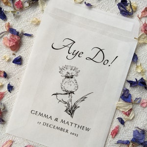Opaque glassine packet for wedding favours. Aye do! is written at the top with an image of a thistle in the centre followed by the couples names and the wedding date.