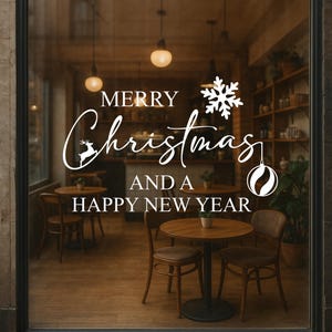 May include: A shop window features a white graphic saying "MERRY Christmas AND A HAPPY NEW YEAR". The design includes a snowflake, reindeer, and ornament. Inside, round tables and chairs are visible, suggesting a cafe or restaurant.