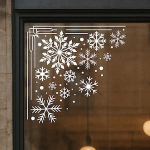 Op de afbeelding: Witte sneeuwvlok raamstickers in verschillende maten en vormen, gerangschikt in een hoekontwerp. De winterthema stickers bevatten grote en kleine sneeuwvlokken en stippen, perfect voor seizoensdecoratie.