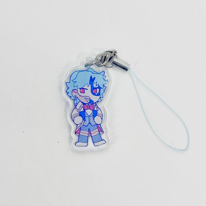 May include: A clear acrylic charm featuring a cartoon character with blue hair and a blue and red outfit. The charm has a silver-colored metal clasp and a light blue lanyard. The character has a red eye and a red bow tie.