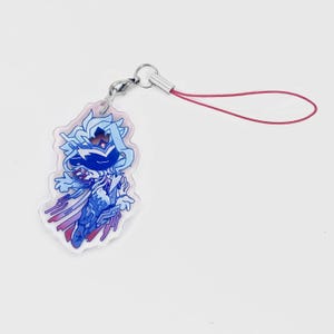 May include: A clear acrylic charm featuring a blue and purple anime-style character design. The charm has a silver-colored clasp and a red lanyard. The character has a crown and cape. The charm is a keychain accessory.
