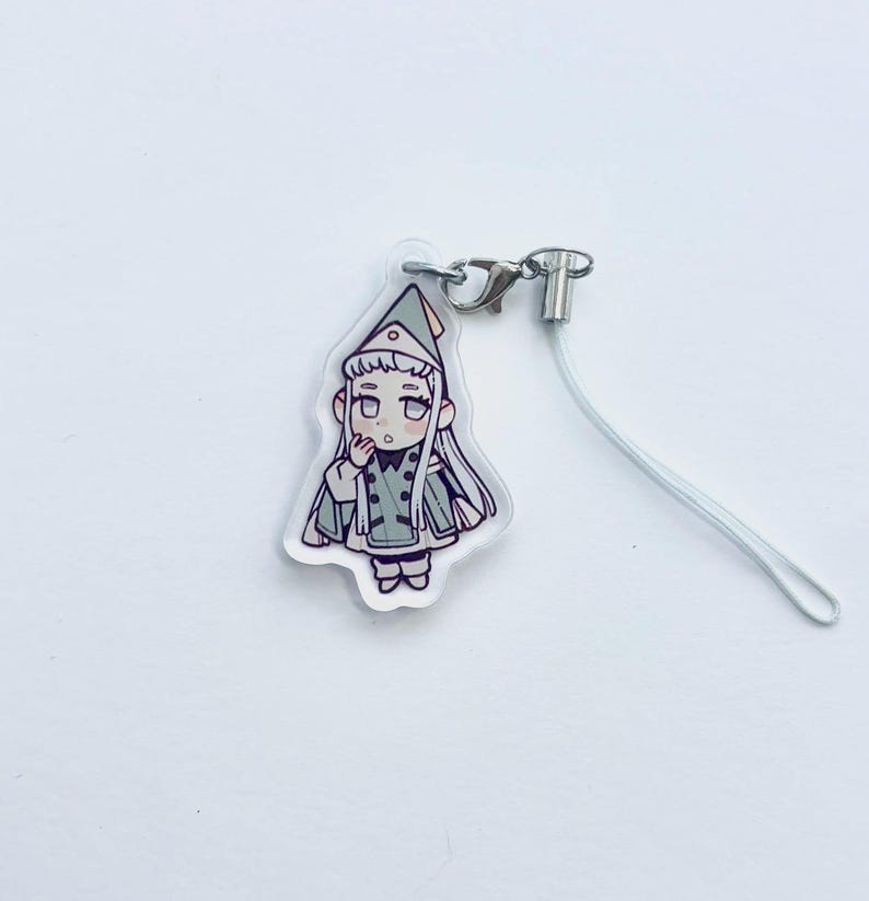 May include: A clear acrylic charm with a cartoon illustration of a character in a green and white outfit. The charm has a silver-coloured clasp and a white lanyard. The character has long white hair and is wearing a hat.