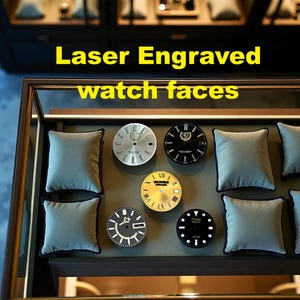 Peut inclure: Une vitrine présentant des cadrans de montre gravés au laser. Les cadrans sont argentés, noirs et dorés. Le texte "Laser Engraved watch faces" est en jaune. Chaque cadran est présenté sur un coussin gris.