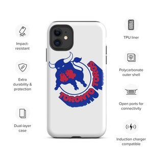 Op de afbeelding: Een witte telefoonhoes met een blauw en rood Toronto Toros logo met een stier. De hoes is stootvast, heeft extra duurzaamheid en bescherming en is dubbelwandig. Het heeft open poorten voor connectiviteit en is compatibel met inductieladen.