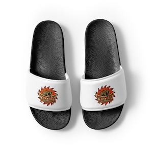 May include: A pair of black and white slide sandals with a white strap featuring a cheetah logo with the text "CHEETAHS" in orange and brown.