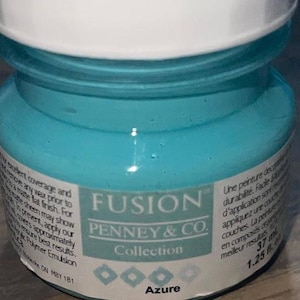 May include: A small, turquoise-colored jar of Fusion mineral paint in the shade "Azure." The label reads "Penney & Co. Collection" and provides details about the paint's coverage and finish. The jar contains 1.25 fl oz of paint.