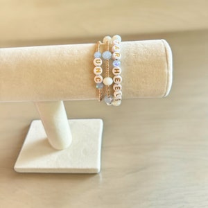 May include: Three beaded bracelets with gold lettering. The bracelets spell out "UNC", "TAR", and "HEELS".