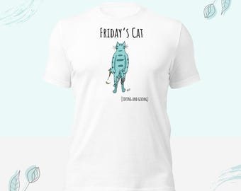 May include: A white short-sleeve t-shirt featuring a graphic of a light blue striped cat standing on its hind legs. The text above reads Friday's Cat and the text below reads (Loving and Giving). The cat holds a small brown object in one paw.