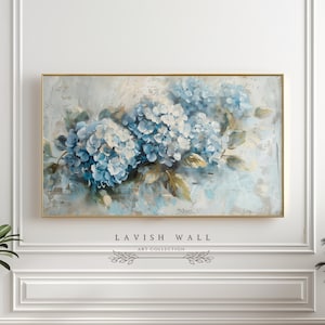 Op de afbeelding: Een schilderij van blauwe hortensia's met groene bladeren op een lichtblauwe achtergrond. Het schilderij is ingelijst in goud.