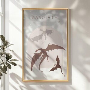 May include: A framed print with a light blue background and the word "BASGIATH" in black text. Three brown dragon silhouettes are flying in a circular archway with a star in the top right corner.