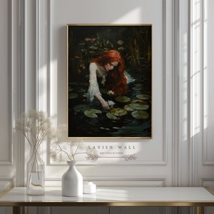 Puede incluir: Una pintura de una mujer con el pelo largo y rojo que se inclina sobre un estanque con nen&uacute;fares. Lleva un vestido blanco y alcanza una flor blanca.