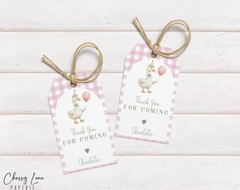 Könnte beinhalten: Zwei Geschenkanhänger mit rosa Vichy-Karo-Rand und einer Aquarellillustration einer Gans, die einen rosa Ballon hält. Auf den Anhängern steht "Thank You For Coming" und sie enthalten ein grünes Herz und den Namen "Charlotte". Jeder Anhänger hat eine Schnurschlaufe.