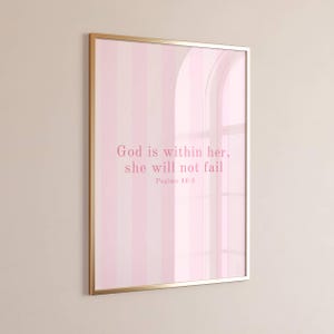 Puede incluir: Un cuadro rectangular en un marco dorado fino con un fondo de rayas verticales en rosa claro y blanco. El texto en el centro dice, God is within her, she will not fail, Psalms 46:5, impreso en una fuente serif de color rosa oscuro.