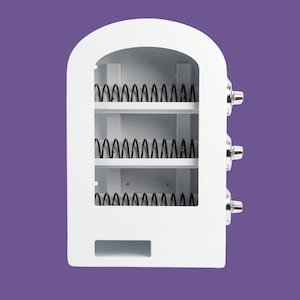 May include: A white vending machine display unit with an arched top, featuring three horizontal shelves equipped with black metal coil dispensers. The right side of the unit has three silver knobs, and there is a rectangular slot at the bottom.