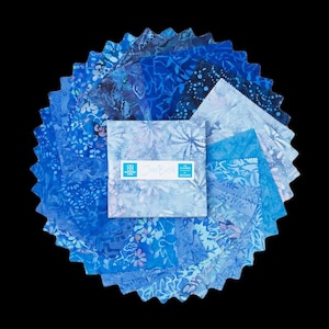 May include: A stack of square fabric pieces in various shades of blue, featuring floral and abstract patterns. A white paper label on the top square displays the text Java Batik 42 Charms 5 inch squares. The edges of the fabric squares are pinked.