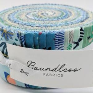 May include: A jelly roll of fabric strips featuring various shades of blue, teal, and white with assorted patterns including sea life and botanical motifs. A white paper band is wrapped around the center with the text Boundless FABRICS.
