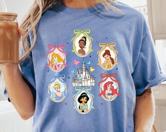 Peut inclure: Un t-shirt bleu clair avec un motif de princesses Disney dans des cadres avec des nœuds. Les princesses sont entourées de cœurs et d'une représentation du château de Cendrillon.