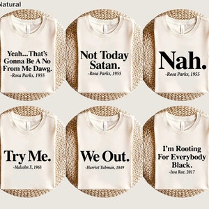 Könnte beinhalten: Sechs weiße T-Shirts mit schwarzem Text auf jedem. Der Text auf den Shirts lautet: "Yeah... That's Gonna Be A No From Me Dawg. -Rosa Parks, 1955", "Not Today Satan. -Rosa Parks, 1955", "Nah. -Rosa Parks, 1955", "Try Me. -Malcolm X, 1963", "We Out. -Harriet Tubman, 1849", und "I'm Rooting For Everybody Black. -Issa Rae, 2017".