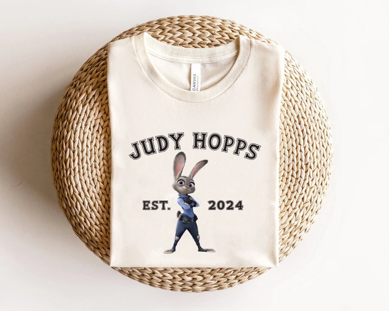 May include: A white t-shirt with a black graphic of Judy Hopps from the movie Zootopia. The graphic includes the text "Judy Hopps" and "Est. 2024".