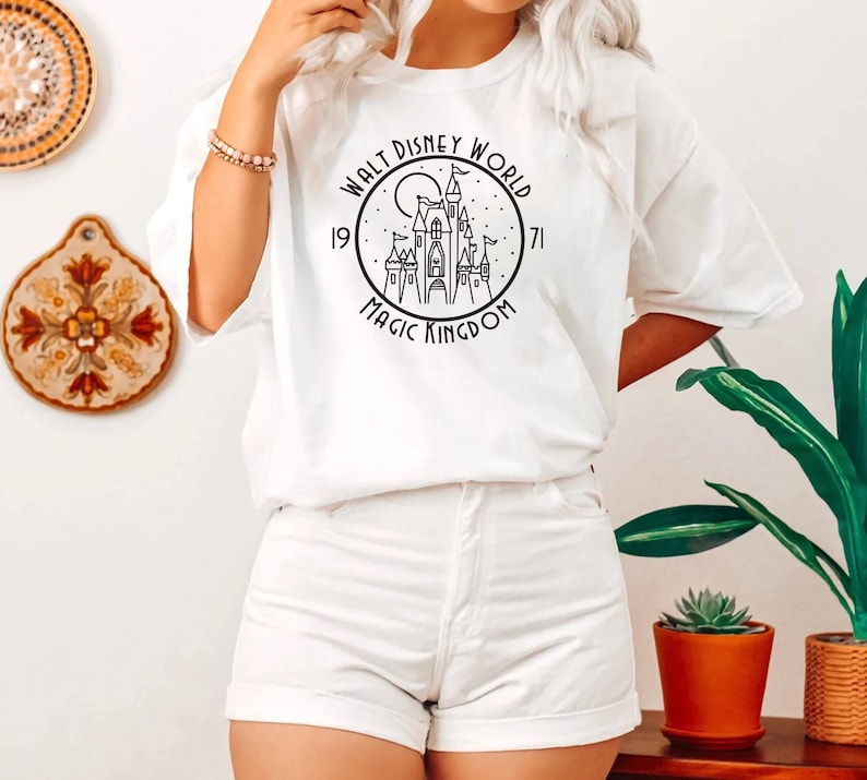 Puede incluir: Camiseta blanca con un gr&aacute;fico negro del castillo de Cenicienta y el texto "Walt Disney World 1971 Magic Kingdom".